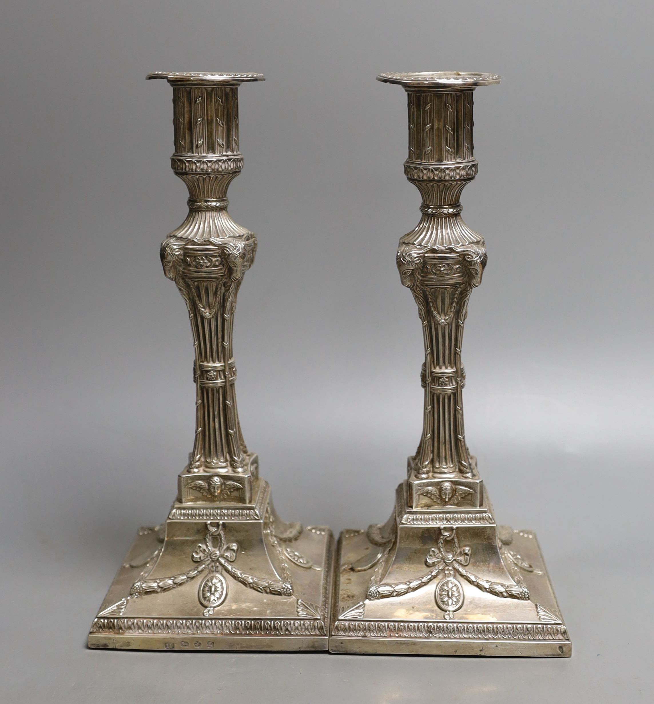A matched pair of George III silver candlesticks, with waisted fluted stems and rams head, winged mask and swag decoration, Joseph Tibbitts, Sheffield, 1775 and George Ashforth & Co, Sheffield, 1775 29.4cm, weighted.